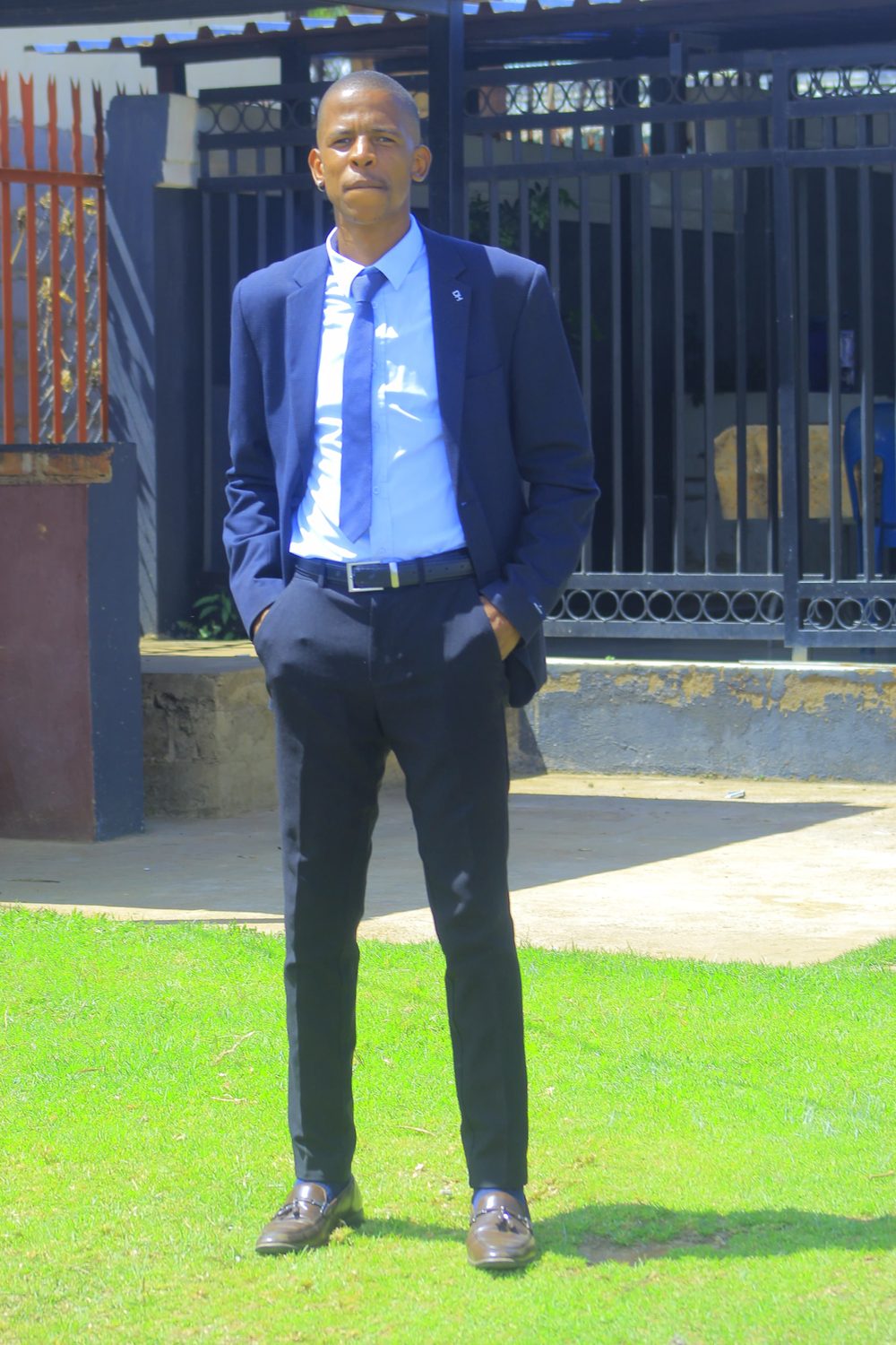 Edward Mawela standing with hands in pockets, wearing a navy suit